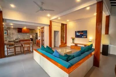 a living room with a blue couch and a kitchen at The Sundara Room in Kerobokan