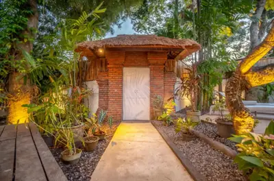 a brick house with a white door and some plants at The Sundara Room in Kerobokan