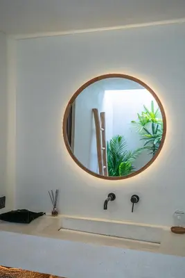 a bathroom sink with a round mirror above it at Villa Luuma 3 - Cozy Umalas Oasis, 1BR Private Villa in Canggu