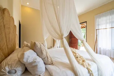 a white bed with curtains and pillows on it at The Hijau Damai Villa in Seminyak
