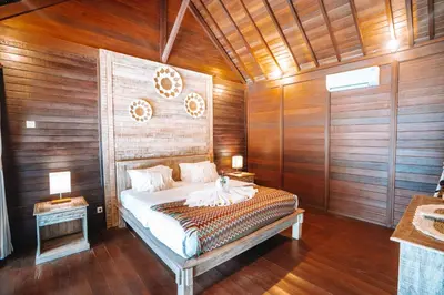 a bedroom with a bed in a room with wooden walls at Villa jepun berawa in Canggu