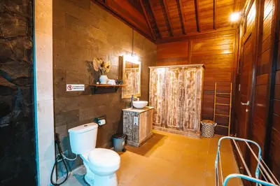 a bathroom with a toilet and a wooden wall at Villa jepun berawa in Canggu