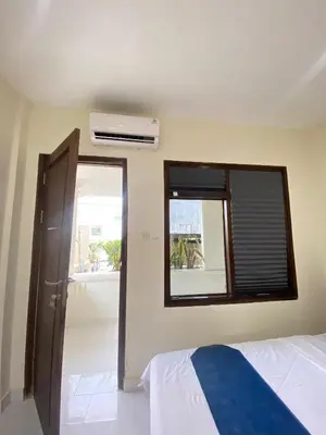 a bedroom with a bed and a window with a air conditioner at SH Hotel - 20 Second to the Bach by Micky Studio R in Legian