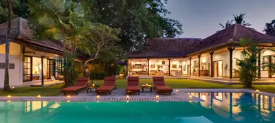 a villa with a swimming pool in front of a house at Villa Delapan Seminyak in Seminyak
