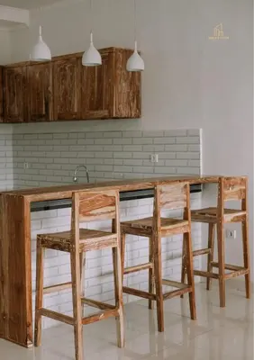a kitchen with three wooden stools around a counter at Mika Estate Property in Seminyak