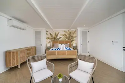 a bedroom with a bed with two chairs and a table at Villa Aclasa Luxery 4BR Retreat in Berawa, Canggu in Canggu