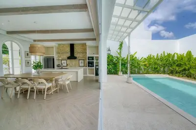 a kitchen and dining room with a table and a swimming pool at Villa Aclasa Luxery 4BR Retreat in Berawa, Canggu in Canggu