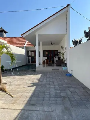 a white house with a patio and a white wall at Villa Cassia Jimbaran in Jimbaran