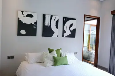 a bedroom with a white bed with four pictures on the wall at Villa Mannah - Managed By Chayah Bali Villa Group in Kuta