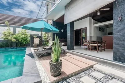 a house with a pool and a blue umbrella at Villa Nakula - Managed By Chayah Bali Villa Group in Seminyak