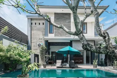 a house with a swimming pool and a blue umbrella at Villa Nakula - Managed By Chayah Bali Villa Group in Seminyak
