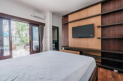 a bedroom with a large bed and a flat screen tv at Villa Nakula - Managed By Chayah Bali Villa Group in Seminyak