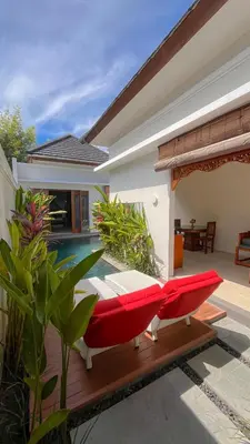 a red couch sitting on a deck next to a house at Maharaja Villas Seminyak by Humus Hospitality in Kerobokan