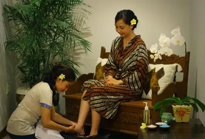 two women are sitting on a bed and one is looking at her foot at Maharaja Villas Seminyak by Humus Hospitality in Kerobokan
