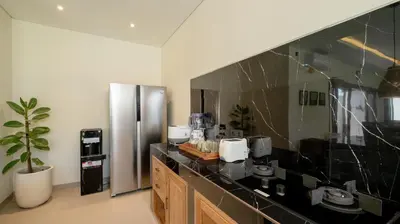 a kitchen with a black counter and a stainless steel refrigerator at The Lange Estate in Seminyak