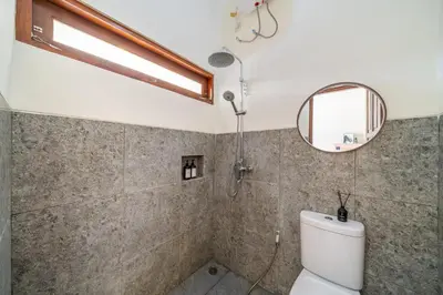 a bathroom with a toilet and a mirror at Jimbaran Retreat in Jimbaran