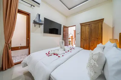 a bedroom with a white bed with roses on it at Jimbaran Retreat in Jimbaran