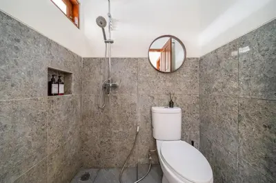 a bathroom with a shower with a toilet and a mirror at Jimbaran Retreat in Jimbaran