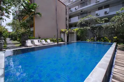 a swimming pool in front of a building at Kamini Legian Hotel in Legian
