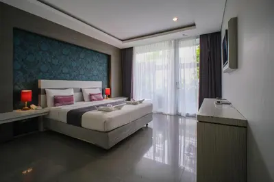 a bedroom with a bed and a large window at Kamini Legian Hotel in Legian