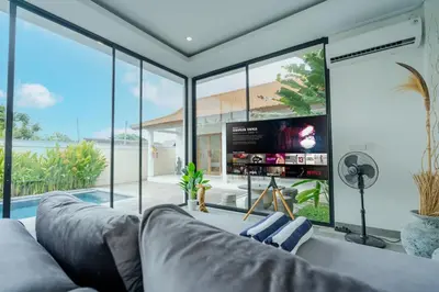 a living room with a couch and large glass windows at The Buddha Villa by Homely Bali in Kerobokan