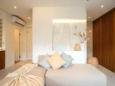 a living room with a white couch with pillows at Berawa Luxury Retreat - The Cruise Canggu in Canggu