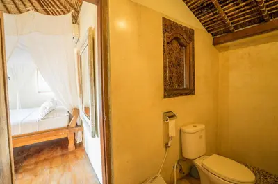 a bathroom with a toilet and a bed in a room at Villa Umah Maya in Seminyak