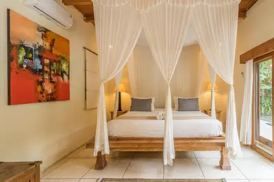 a bedroom with a canopy bed and a window at Villa Umah Maya in Seminyak