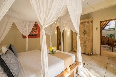 a bedroom with a bed with white drapes at Villa Umah Maya in Seminyak
