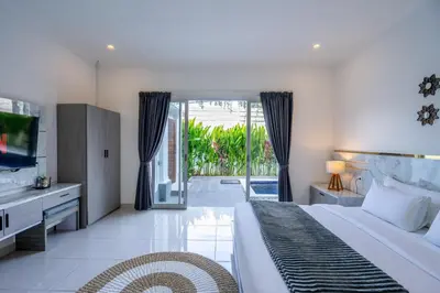 a bedroom with a bed and a tv and a sliding glass door at The Kakadu - A new modern 2BR Villa with private pool in Seminyak in Seminyak