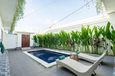 a patio with a swimming pool and two chairs at The Kakadu - A new modern 2BR Villa with private pool in Seminyak in Seminyak