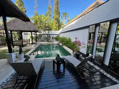a swimming pool with chairs and a cat sitting on a table at Villa Mawar Seminyak in Seminyak