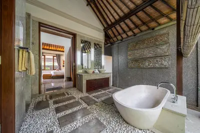 a bathroom with a bath tub and a bedroom at Beachside Villa Di Bucu in Canggu