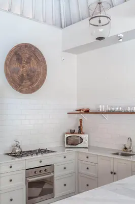 a white kitchen with a stove and a microwave at Villa Seni in Seminyak