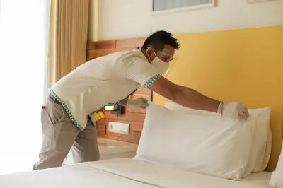 a man putting a pillow on a bed at Bali Paragon Resort Hotel in Jimbaran