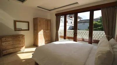 a bedroom with a white bed and a large window at SummerVille Nusa Dua by REJA Villas in Nusa Dua