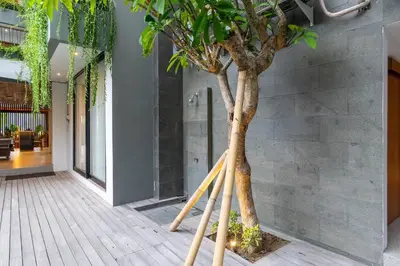 a tree in a room with bamboo poles around it at LOI Mansion Managed by ARM One Hundred in Seminyak