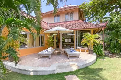 a house with a patio with chairs and an umbrella at Two bedroom Villa in a beautyful tropical garden in Seminyak