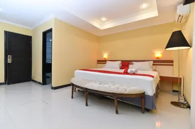 a bedroom with a large bed and a bench at RedDoorz Plus near Mall Bali Galeria 2 in Denpasar