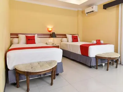 a hotel room with two beds and two tables at RedDoorz Plus near Mall Bali Galeria 2 in Denpasar