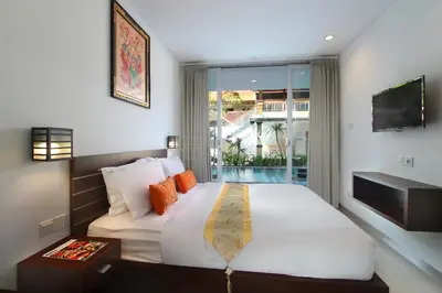 a bedroom with a large white bed and a balcony at Lotus Tirta Seminyak in Seminyak