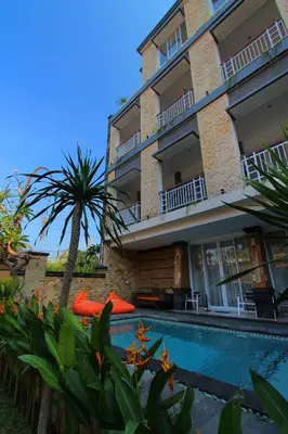 a hotel with a swimming pool in front of a building at Lotus Tirta Seminyak in Seminyak