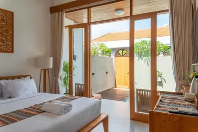 a bedroom with a bed and a sliding glass door at Comoda Seminyak in Seminyak