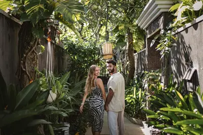 a man and a woman walking through a garden at Ini Vie Villa Seminyak by Ini Vie Hospitality in Legian