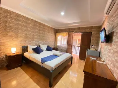 a bedroom with a bed and a flat screen tv at ABI Hotel - 1 minute to the Beach and 1 second to the Mall in Ngurah Rai International Airport