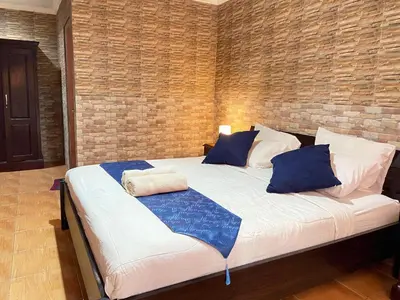 a large bed in a room with a brick wall at ABI Hotel - 1 minute to the Beach and 1 second to the Mall in Ngurah Rai International Airport