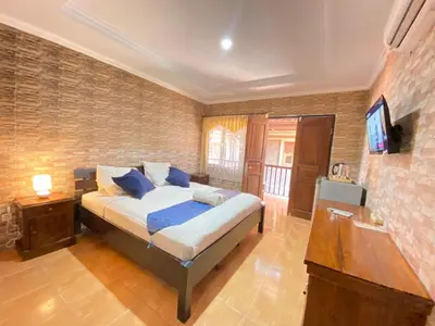 a bedroom with a bed with blue pillows and a television at ABI Hotel - 1 minute to the Beach and 1 second to the Mall in Ngurah Rai International Airport
