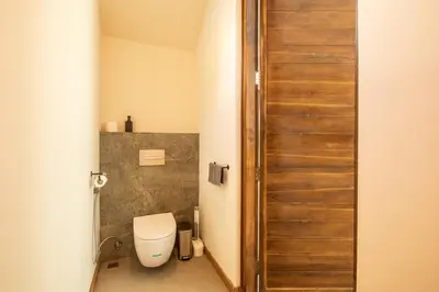 a bathroom with a toilet and a wooden door at Chic Modern 3BR Villa, Enclosed Living Room in Canggu