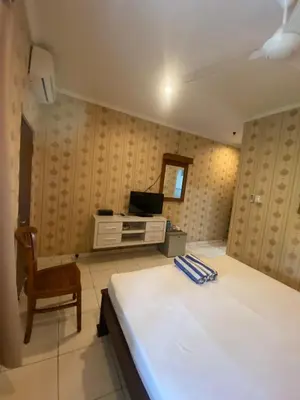a bedroom with a bed and a chair and a television at SC Hotel - 1 Minute to the Beach By Micky Studio in Badung