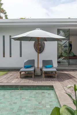 a patio with two chairs and an umbrella at Incredible 3BR Villa In The Heart Of Seminyak in Seminyak